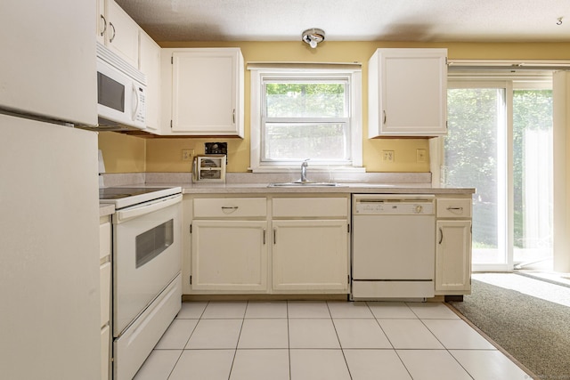 kitchen featuring white appliances, a sink, light countertops, white cabinets, and light tile patterned floors