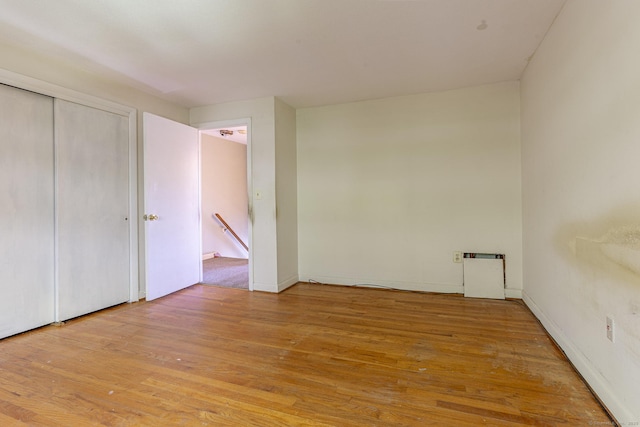 unfurnished bedroom with wood finished floors, a closet, and baseboards