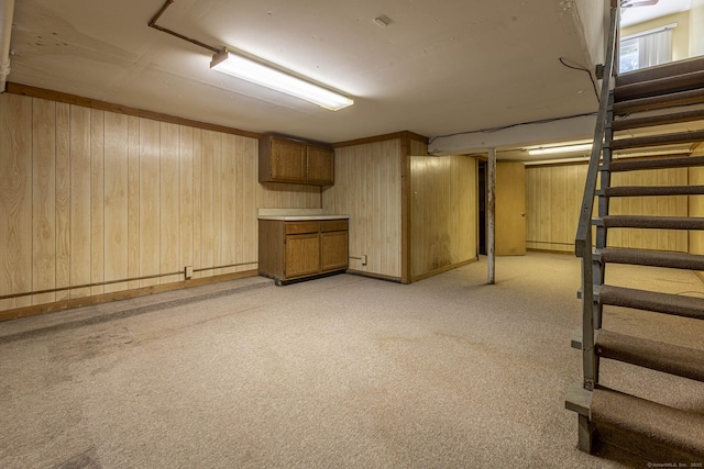 finished basement with stairway, wood walls, and light colored carpet