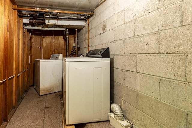 washroom with washing machine and clothes dryer and concrete block wall