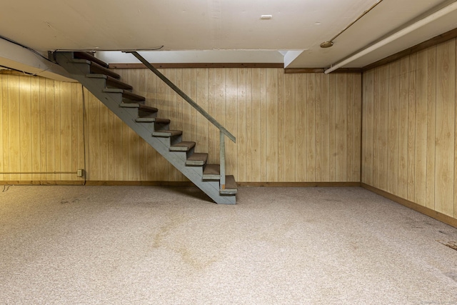 finished basement with wood walls, stairway, and carpet flooring