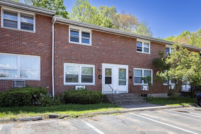 townhome / multi-family property with brick siding, entry steps, and uncovered parking