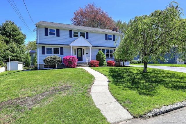 view of front of home with a chimney, a shed, a front yard, and an outdoor structure