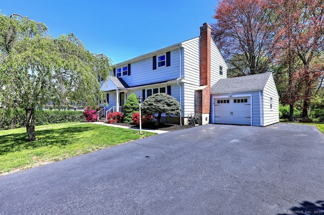 view of front of property featuring a chimney, a front lawn, a garage, and driveway