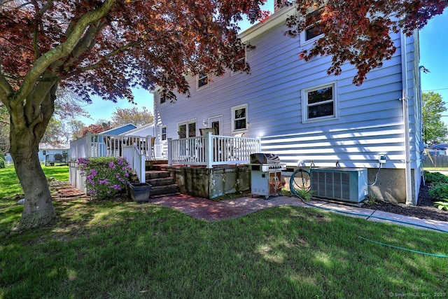 rear view of house with cooling unit, a deck, and a yard