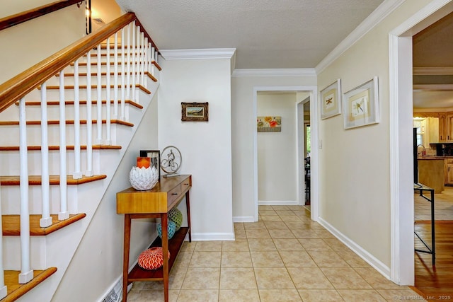 entryway featuring stairway, crown molding, a textured ceiling, baseboards, and light tile patterned floors