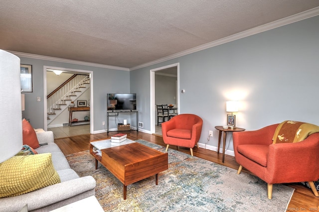 living area with stairway, wood finished floors, crown molding, baseboards, and a textured ceiling