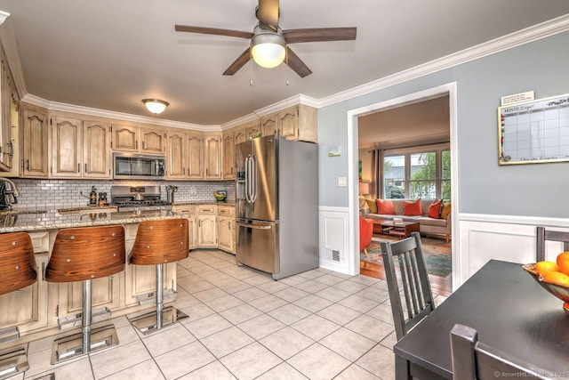 kitchen featuring stainless steel appliances, ceiling fan, light tile patterned floors, light stone countertops, and ornamental molding