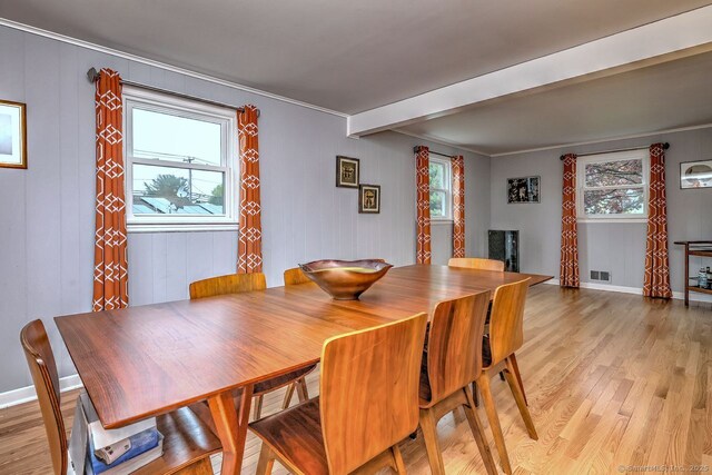 dining room featuring light wood finished floors, beamed ceiling, and baseboards