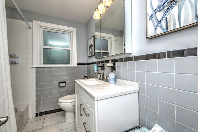 bathroom with tile walls, toilet, vanity, marble look tile flooring, and shower / bath combo