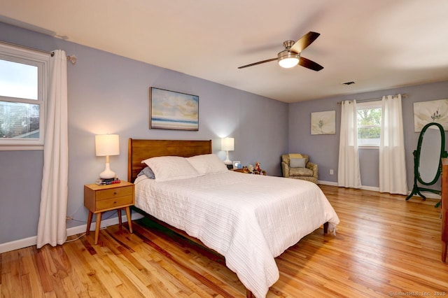 bedroom with light wood finished floors, baseboards, and ceiling fan