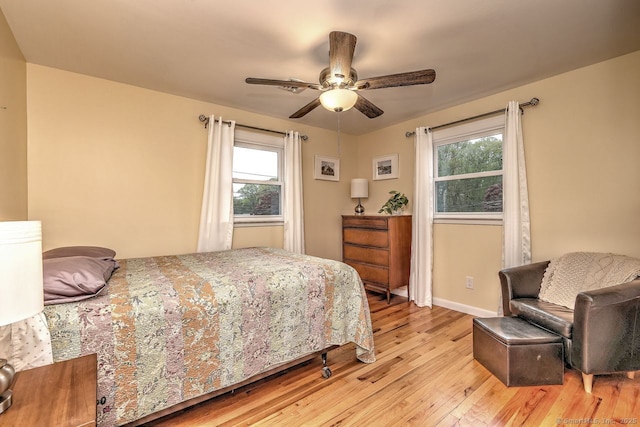 bedroom with light wood-type flooring, baseboards, and a ceiling fan