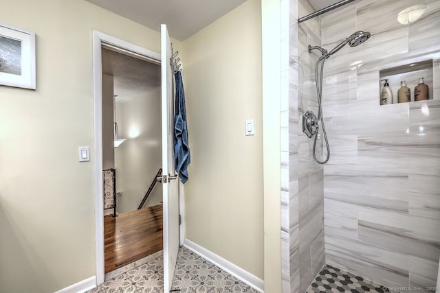 bathroom featuring a tile shower and baseboards