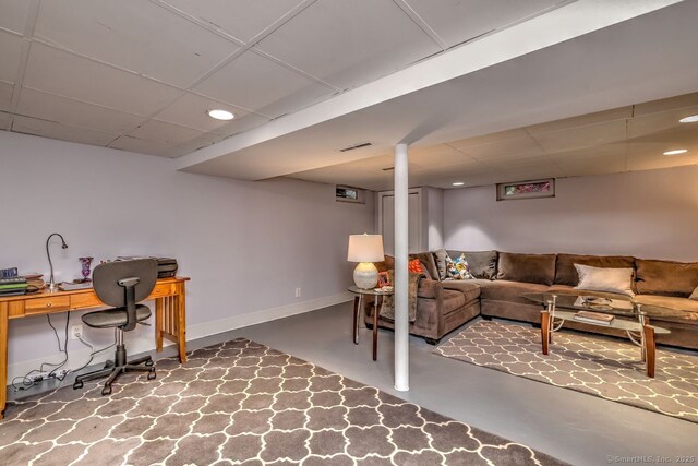 living room featuring a drop ceiling, finished concrete flooring, recessed lighting, an office area, and baseboards