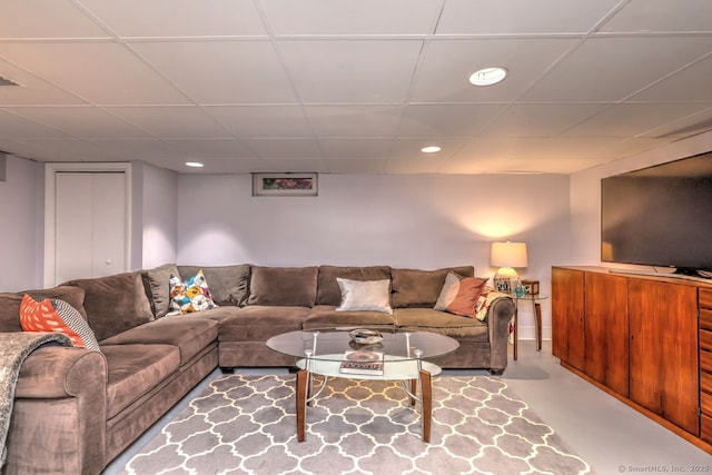 living room featuring a paneled ceiling, recessed lighting, and finished concrete flooring
