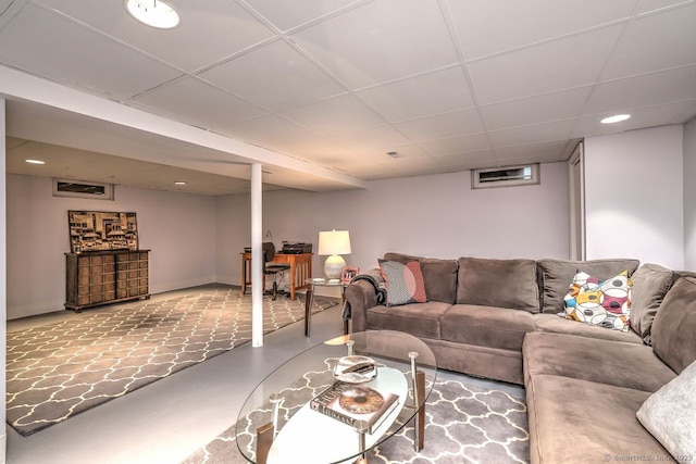 living room featuring a drop ceiling, recessed lighting, concrete floors, and baseboards
