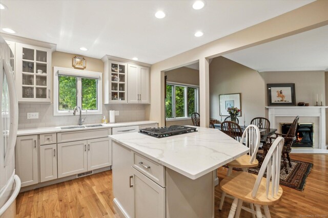 8 Cottonwood Ct Unit 8, Granby, CT 06035 - kitchen with a sink, a kitchen bar, light wood finished floors, tasteful backsplash, and plenty of natural light