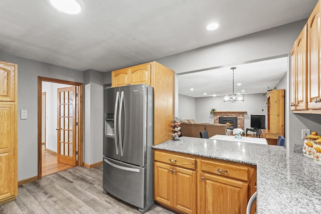 74R Green Ln, Durham, CT 06422 - kitchen with stainless steel fridge, light wood-type flooring, a brick fireplace, recessed lighting, and decorative light fixtures