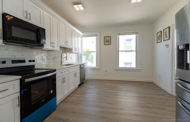 kitchen featuring appliances with stainless steel finishes, a sink, light countertops, and white cabinetry