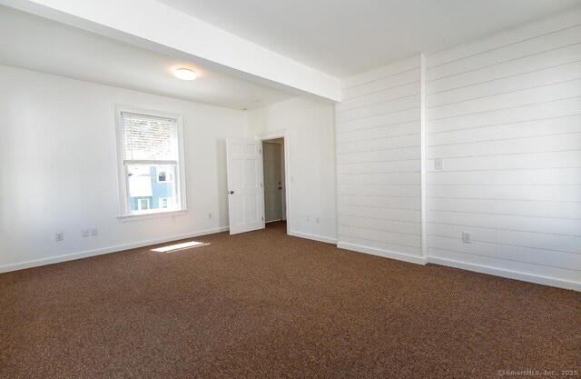 unfurnished room featuring dark carpet and baseboards