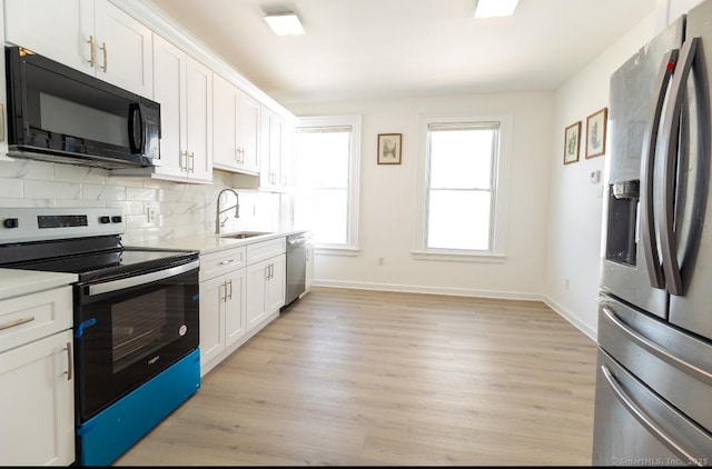 kitchen with stainless steel appliances, a sink, light countertops, baseboards, and light wood-type flooring
