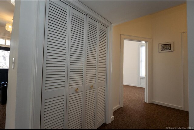 hallway with carpet, baseboards, and a chandelier