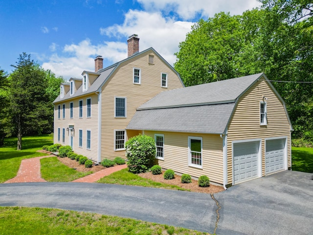 134 School House Rd, Old Saybrook, CT 06475 - view of property exterior featuring asphalt driveway, a chimney, a gambrel roof, a yard, and a shingled roof