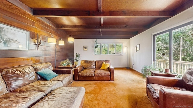 carpeted living area featuring beamed ceiling, wooden walls, and baseboards
