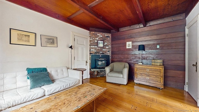 living room with a wood stove, wooden ceiling, beam ceiling, wood-type flooring, and wood walls