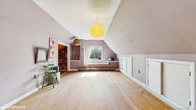 additional living space with a baseboard heating unit, lofted ceiling, and baseboards