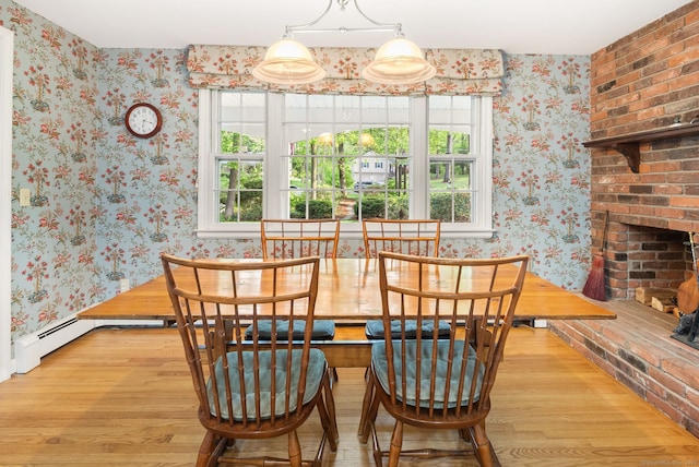 dining area with wallpapered walls, wood finished floors, and a fireplace
