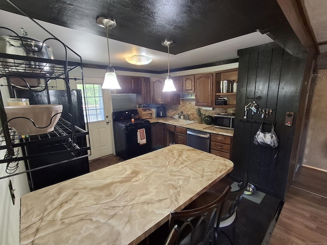 kitchen featuring stainless steel appliances, a sink, dark wood finished floors, light countertops, and backsplash