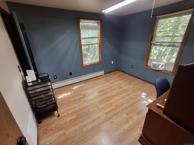 spare room featuring a baseboard radiator, wood finished floors, and a desk