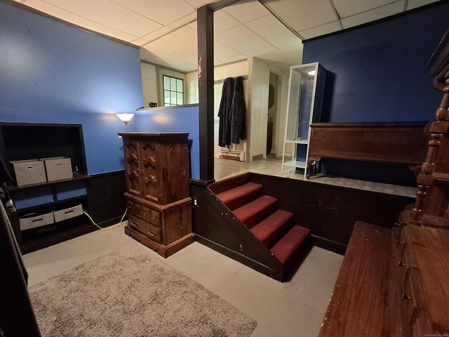 bedroom featuring a drop ceiling and finished concrete floors