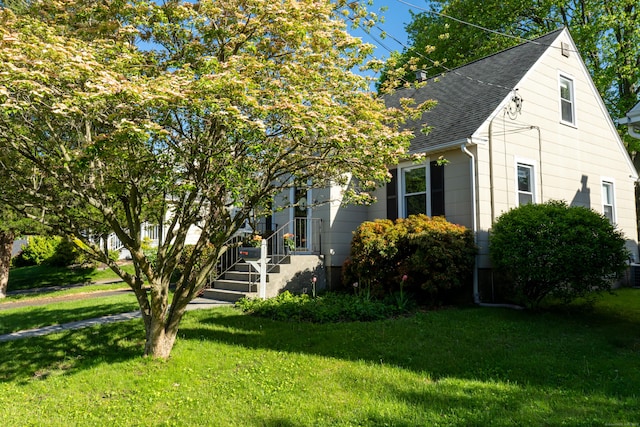 view of front of property featuring roof with shingles and a front lawn