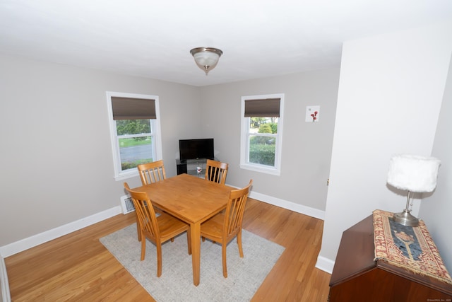 dining room featuring plenty of natural light, baseboards, and light wood finished floors