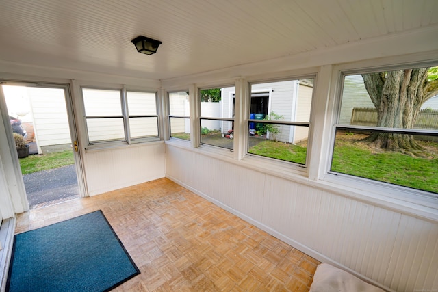 unfurnished sunroom featuring baseboards and wood walls