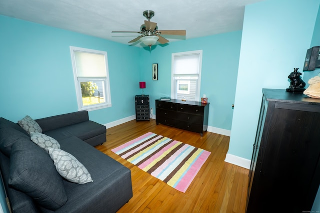 living room featuring baseboards, wood finished floors, and a ceiling fan