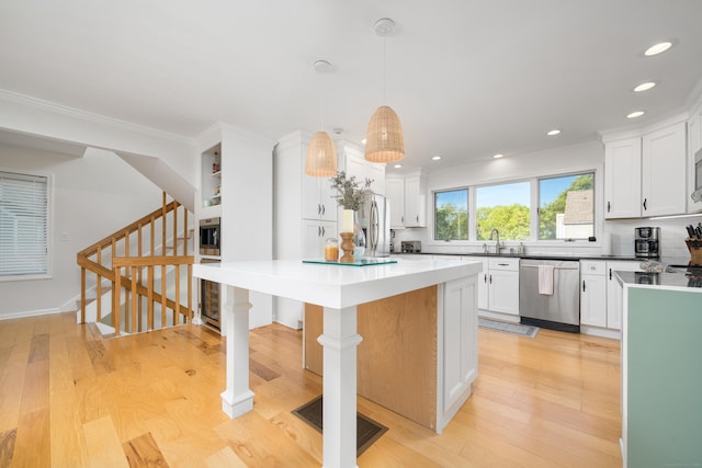 kitchen featuring appliances with stainless steel finishes, a sink, a kitchen island, white cabinetry, and recessed lighting