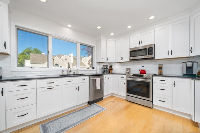 kitchen featuring stainless steel appliances, a sink, healthy amount of natural light, white cabinets, and recessed lighting