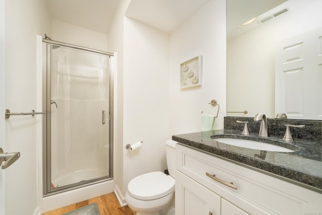 full bath featuring a shower stall, wood finished floors, toilet, vanity, and baseboards