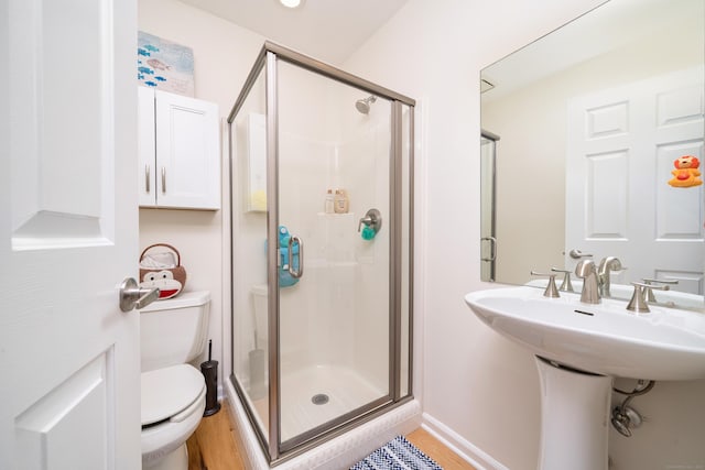 bathroom with toilet, a shower stall, and wood finished floors