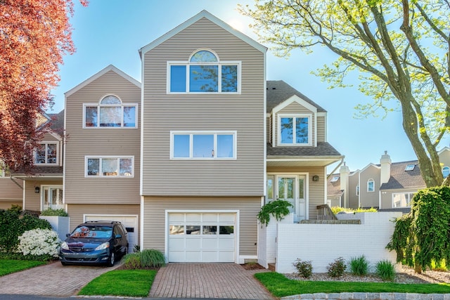 view of front of property featuring an attached garage, decorative driveway, and fence