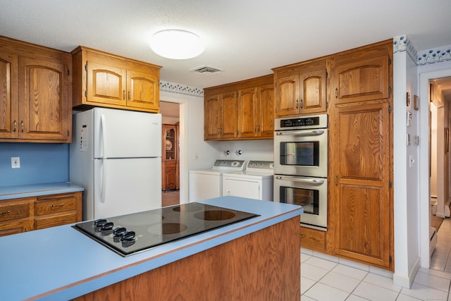 kitchen with freestanding refrigerator, stainless steel double oven, washing machine and clothes dryer, black electric stovetop, and brown cabinets