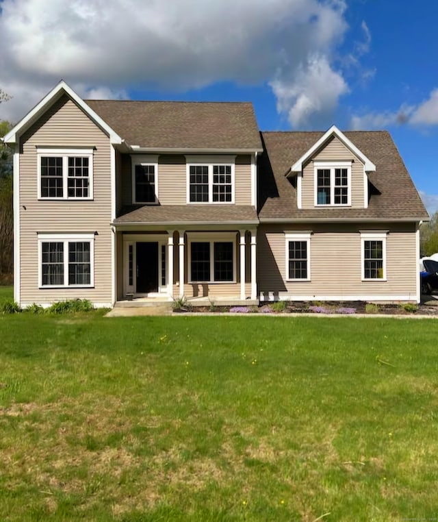 view of front facade with a front yard and roof with shingles