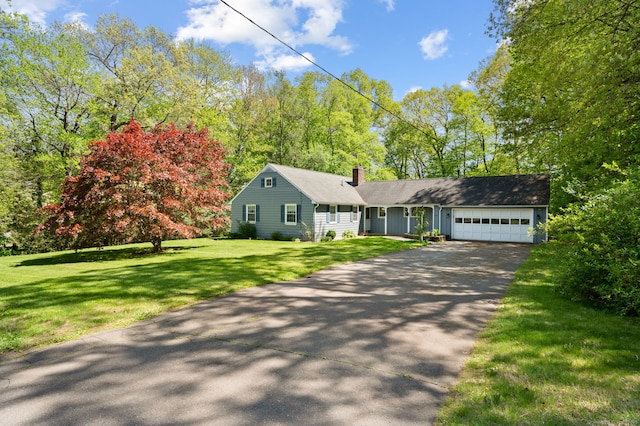 view of front of property with driveway, a chimney, an attached garage, and a front yard