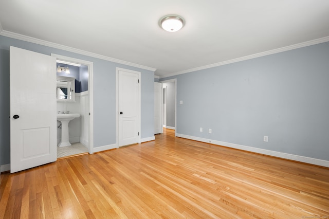 unfurnished bedroom featuring light wood-style flooring, ornamental molding, baseboards, and ensuite bathroom