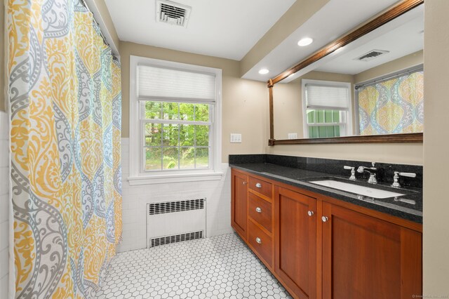 full bath with radiator, tile walls, vanity, recessed lighting, and a wainscoted wall
