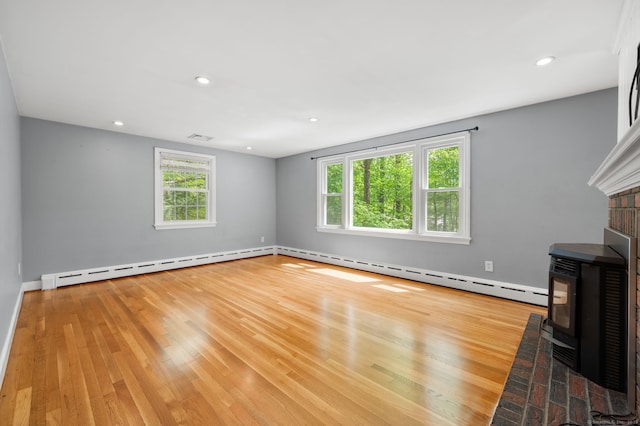unfurnished living room featuring healthy amount of natural light, wood finished floors, a wood stove, and recessed lighting
