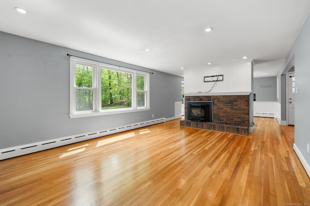 unfurnished living room with a baseboard radiator, light wood-type flooring, a fireplace, recessed lighting, and baseboards